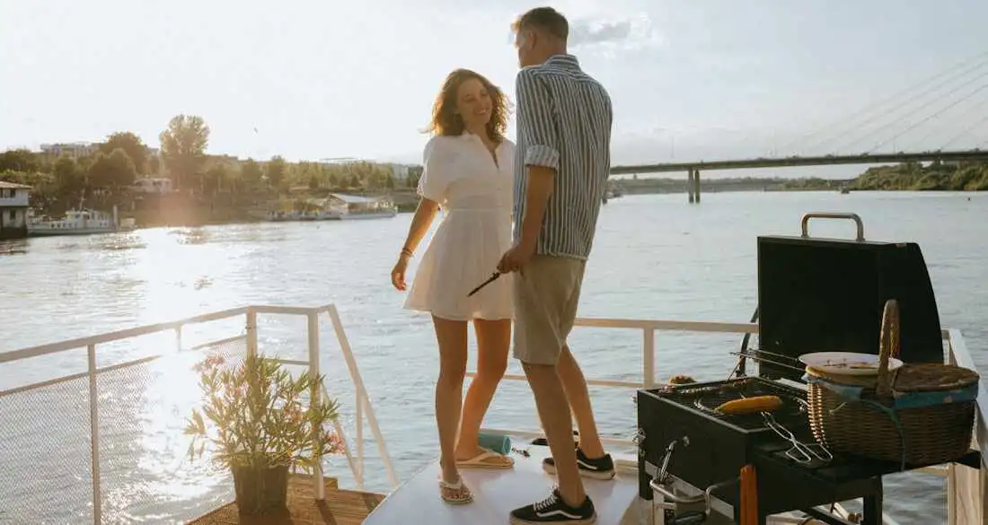 Traveler sipping coffee at a scenic outdoor café, journaling with sunglasses and a hat beside her.